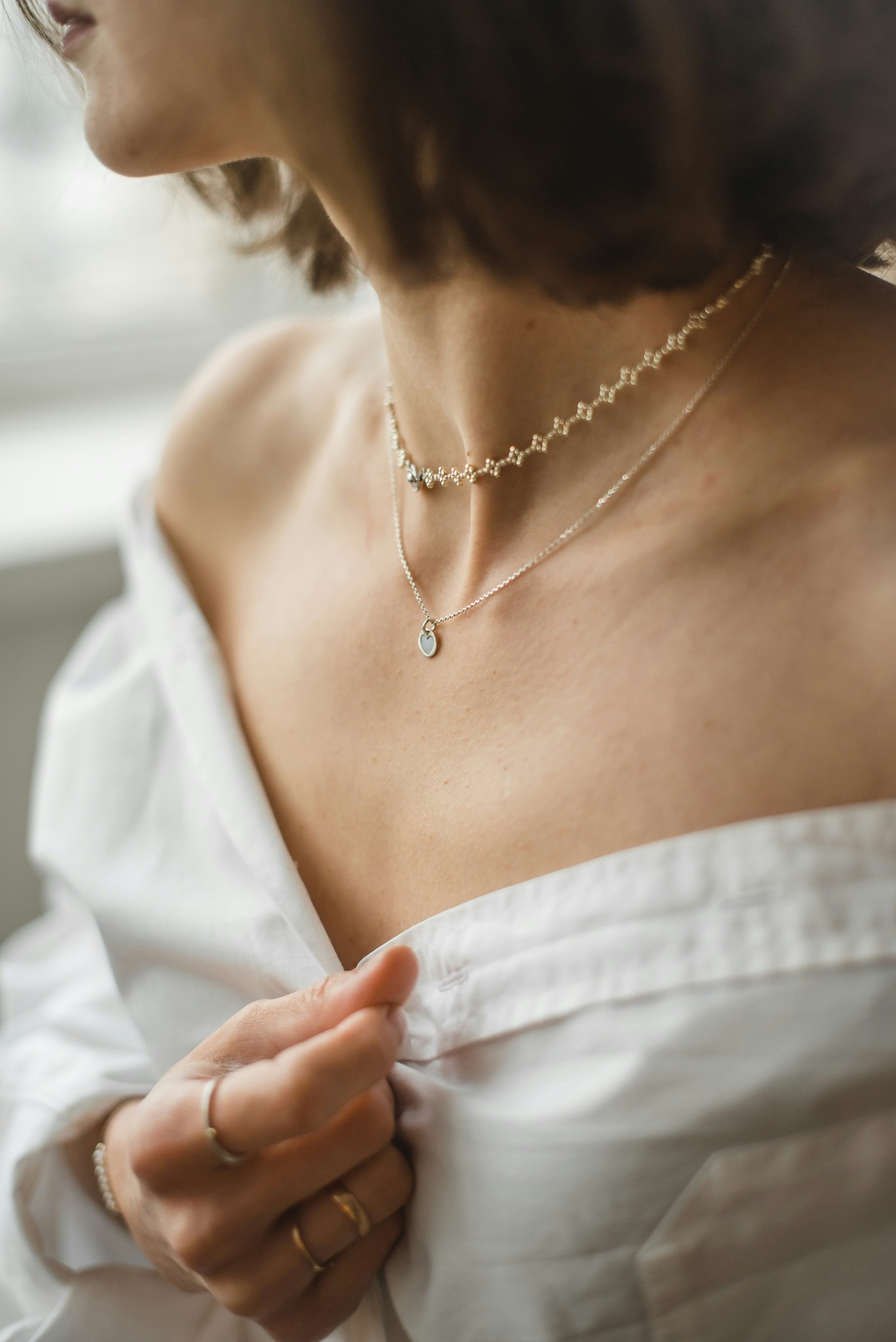 Person wearing layered necklaces for jewellery styling and care guidance